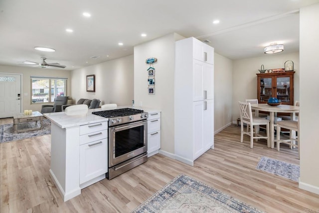 kitchen featuring stainless steel gas range oven, light wood-type flooring, white cabinetry, and recessed lighting