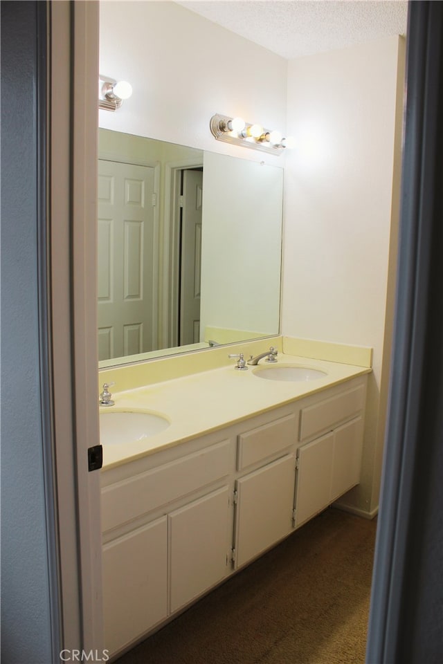 bathroom with double vanity, a textured ceiling, and a sink