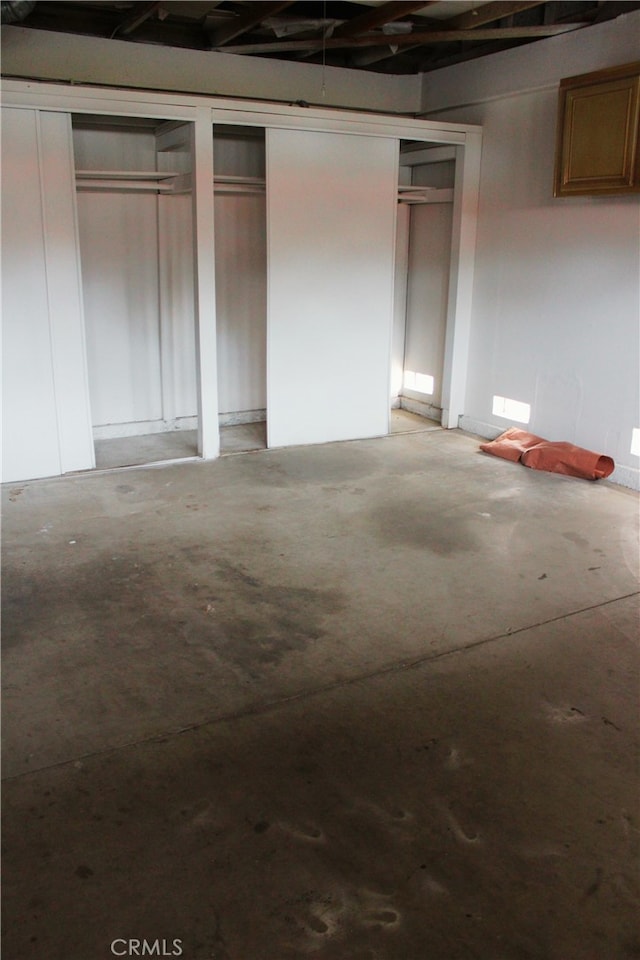 unfurnished bedroom with concrete flooring and multiple closets