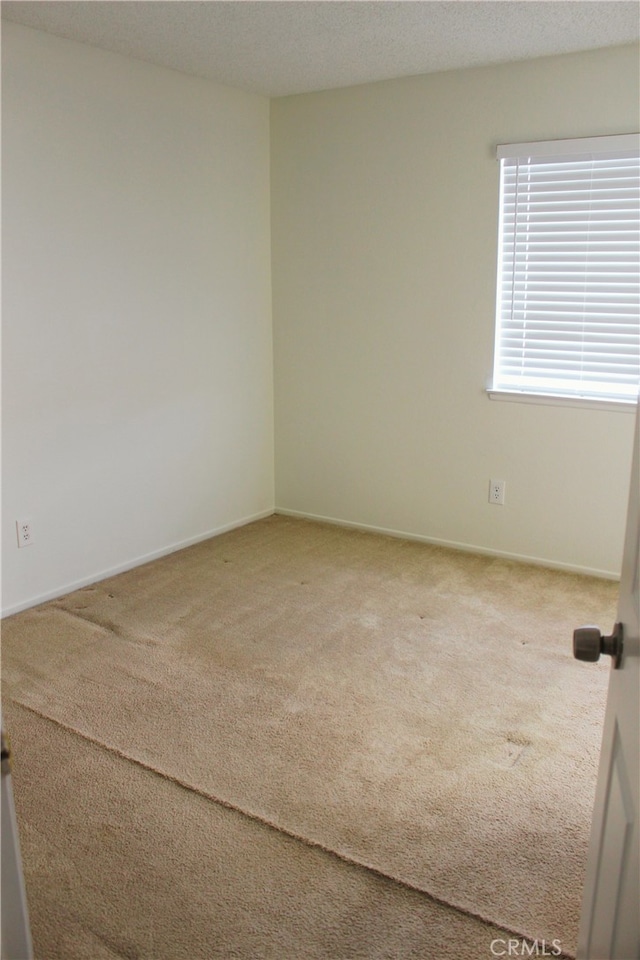 carpeted spare room with a textured ceiling and baseboards