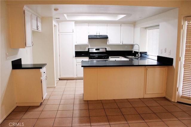 kitchen featuring a peninsula, stainless steel range oven, white cabinetry, and a sink