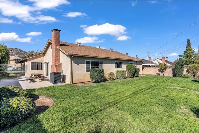 rear view of property featuring fence, a lawn, and stucco siding