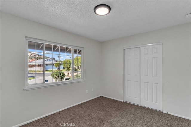 unfurnished bedroom featuring a textured ceiling, a closet, carpet flooring, and baseboards