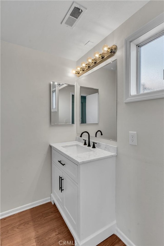 bathroom featuring vanity, wood finished floors, visible vents, and baseboards