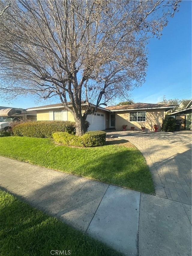 ranch-style house with a front lawn, an attached garage, and stucco siding