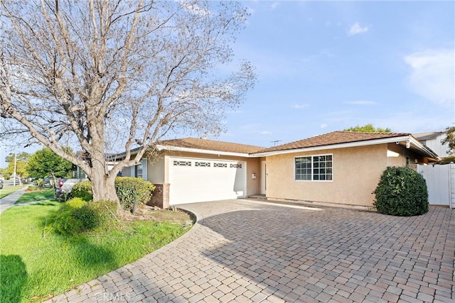 ranch-style home featuring decorative driveway, an attached garage, and stucco siding