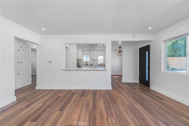 unfurnished living room featuring recessed lighting, dark wood-style flooring, and baseboards