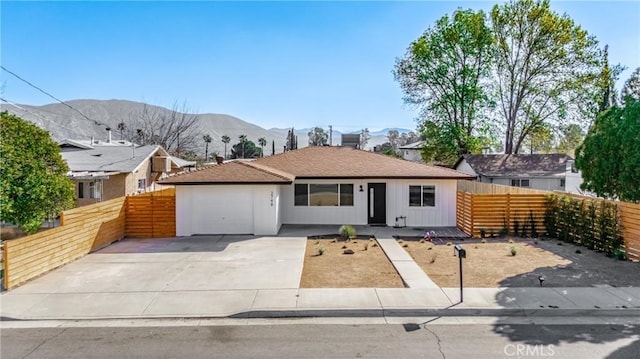 view of front of property featuring a garage, fence private yard, a mountain view, and driveway