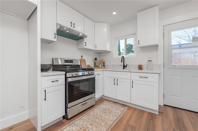 kitchen with white cabinets, a sink, stainless steel range with gas stovetop, and under cabinet range hood