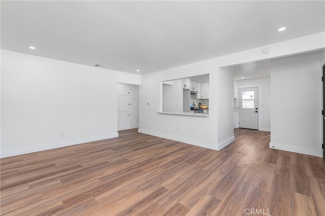 unfurnished living room featuring visible vents, baseboards, wood finished floors, and recessed lighting