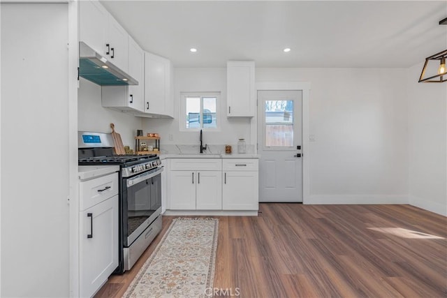 kitchen with under cabinet range hood, white cabinets, light countertops, stainless steel range with gas cooktop, and dark wood-style floors