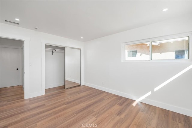 unfurnished bedroom with a closet, wood finished floors, visible vents, and recessed lighting