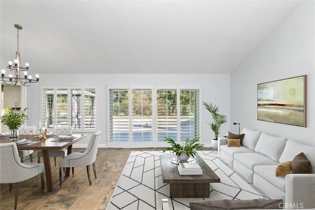 living area featuring a chandelier, lofted ceiling, a healthy amount of sunlight, and wood finished floors