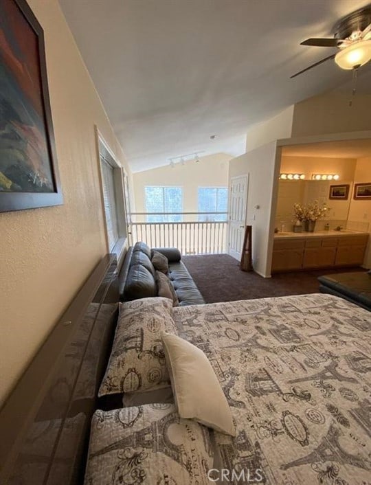 bedroom with lofted ceiling, dark carpet, connected bathroom, and a ceiling fan