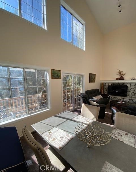 dining area featuring a fireplace, rail lighting, and a towering ceiling