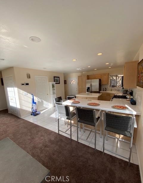 kitchen with light carpet, light tile patterned floors, light countertops, stainless steel refrigerator with ice dispenser, and recessed lighting