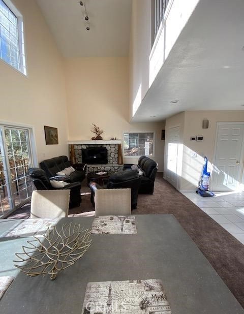 carpeted living room featuring a high ceiling, a fireplace, and tile patterned floors