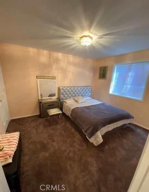 bedroom featuring dark carpet and baseboards