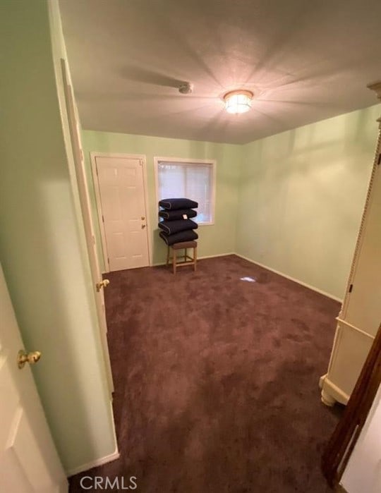 interior space featuring dark carpet and baseboards