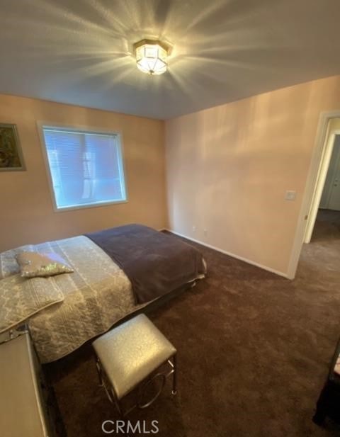 unfurnished bedroom featuring baseboards and dark colored carpet