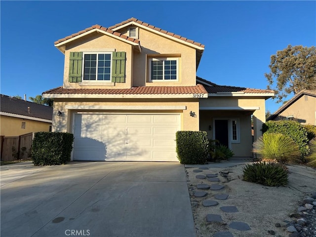 view of front of home with a garage, a tile roof, concrete driveway, and stucco siding