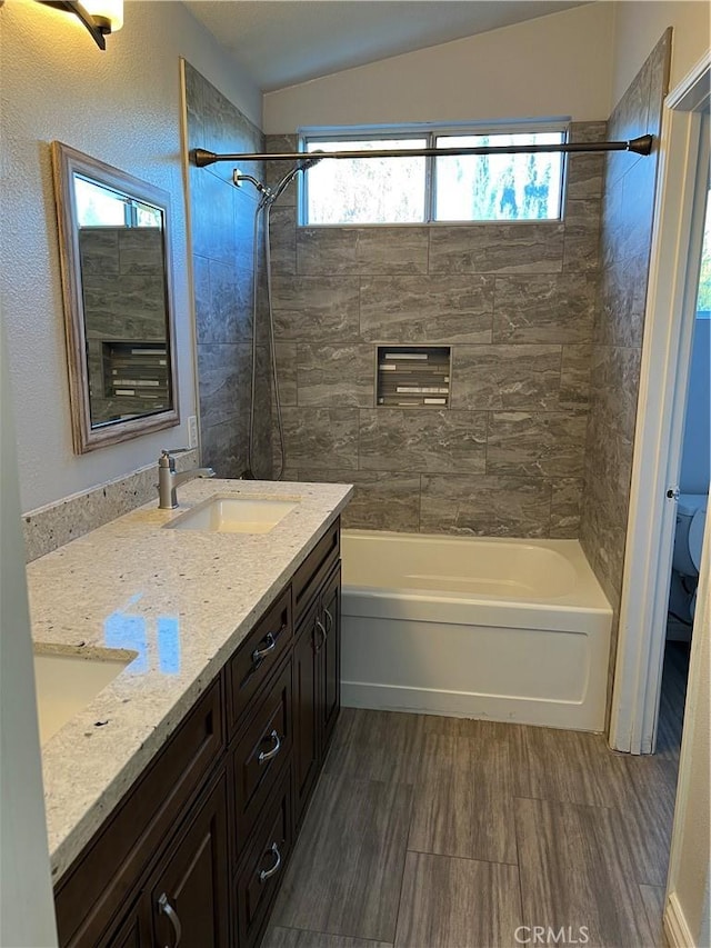 full bathroom featuring double vanity, toilet, lofted ceiling, tub / shower combination, and a sink