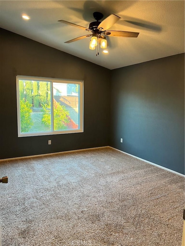 carpeted spare room with vaulted ceiling, a textured ceiling, baseboards, and ceiling fan