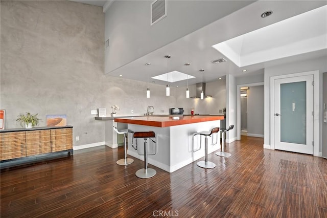 kitchen with a breakfast bar, visible vents, a sink, and wood finished floors