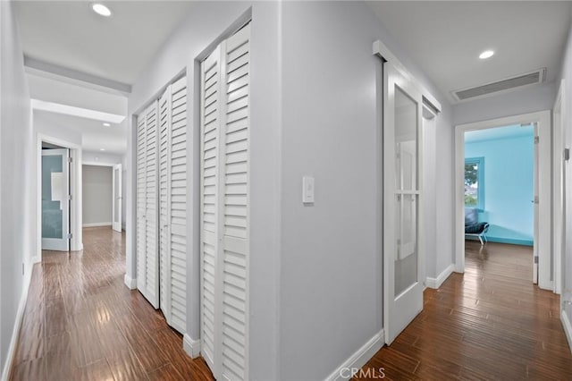 hall featuring baseboards, visible vents, dark wood-style flooring, and recessed lighting