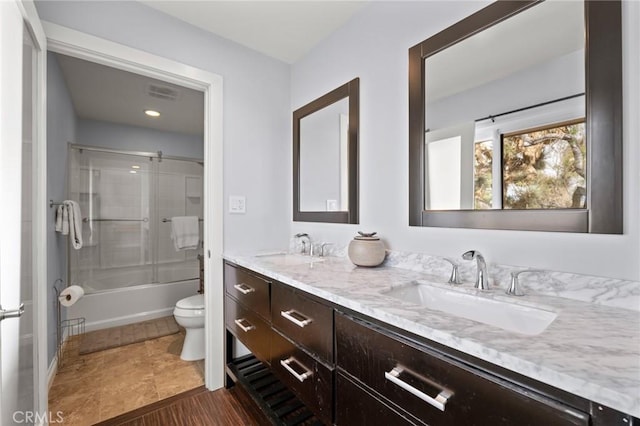 bathroom featuring double vanity, visible vents, toilet, and a sink