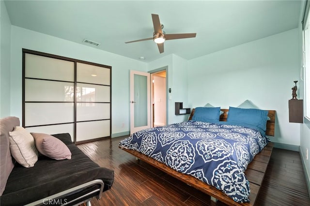 bedroom with ceiling fan, wood finished floors, visible vents, and baseboards