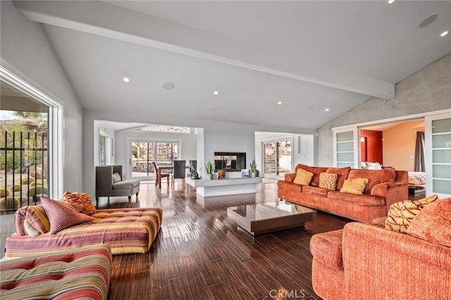 living room with vaulted ceiling with beams, a fireplace with raised hearth, and wood finished floors