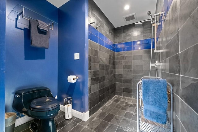 full bath with toilet, a tile shower, visible vents, and baseboards