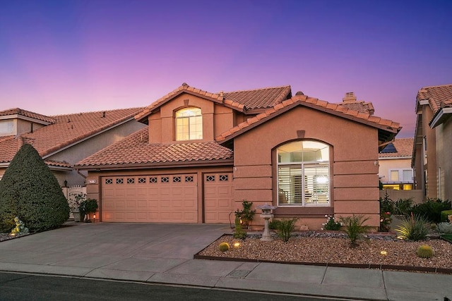 mediterranean / spanish-style home featuring concrete driveway, a chimney, a tiled roof, an attached garage, and stucco siding