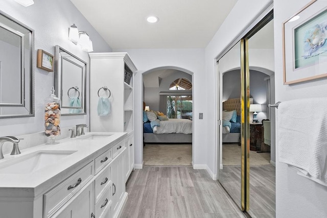 full bathroom with double vanity, wood finished floors, a sink, and ensuite bathroom