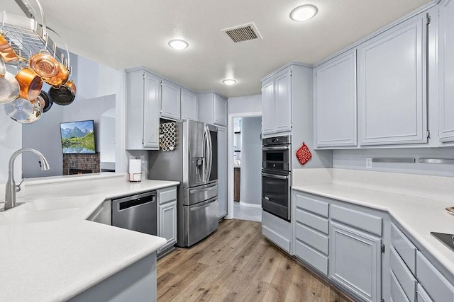 kitchen featuring light countertops, stainless steel appliances, a sink, visible vents, and light wood-style flooring
