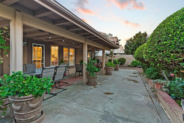 patio terrace at dusk with outdoor dining area and fence