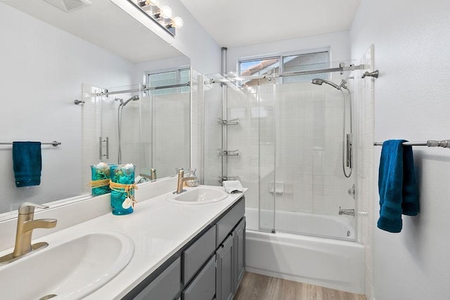 full bath featuring combined bath / shower with glass door, a sink, double vanity, and wood finished floors
