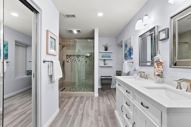 bathroom featuring visible vents, a sink, a shower stall, and wood finished floors