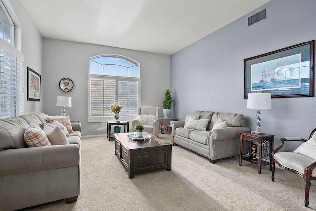 living area with baseboards, visible vents, and light colored carpet