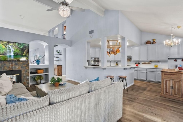 living area featuring beam ceiling, visible vents, a brick fireplace, wood finished floors, and baseboards