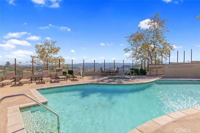 pool featuring fence, a hot tub, and a patio