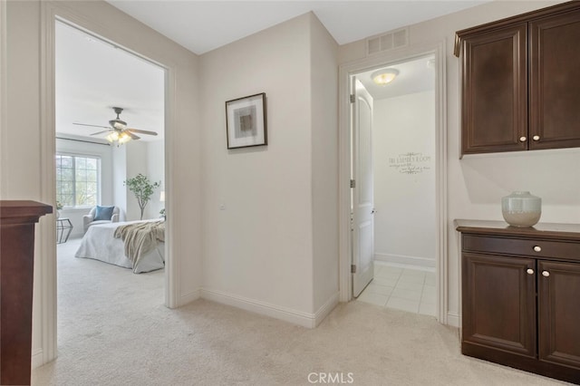 hall with light carpet, visible vents, and baseboards