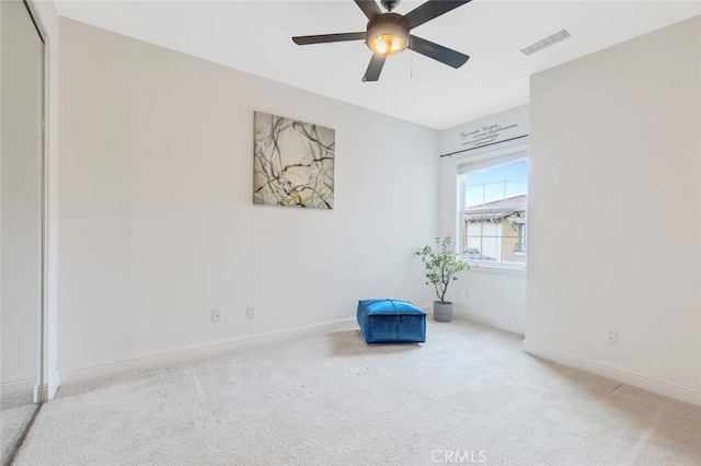 interior space with baseboards, a ceiling fan, visible vents, and light colored carpet