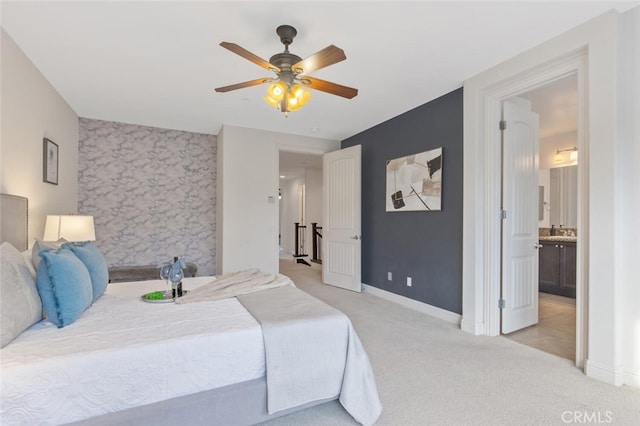 bedroom with light carpet, an accent wall, ceiling fan, and baseboards