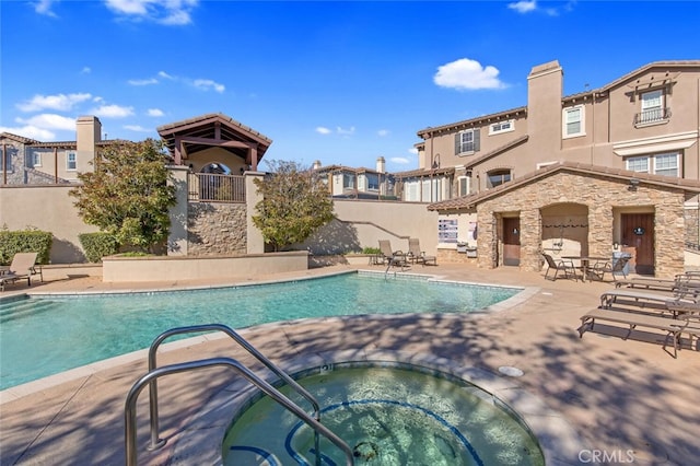 community pool featuring a residential view, fence, a community hot tub, and a patio