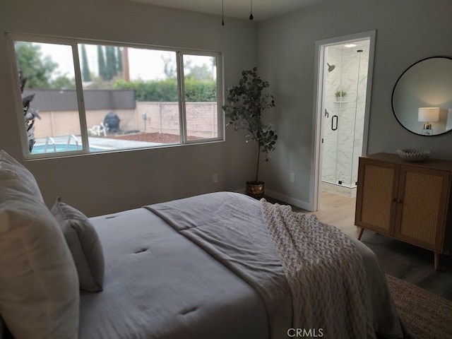 bedroom featuring connected bathroom, baseboards, and light wood-style flooring