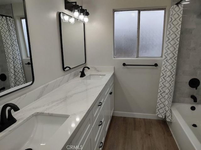 full bath with a sink, baseboards, wood finished floors, and double vanity