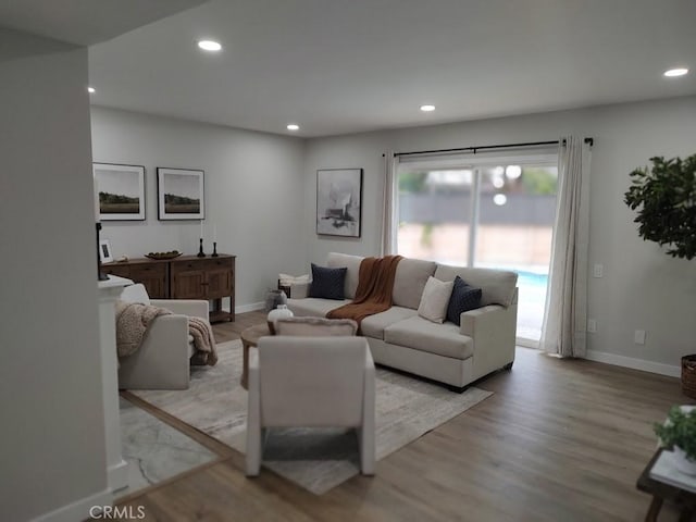 living room with recessed lighting, light wood-type flooring, and baseboards