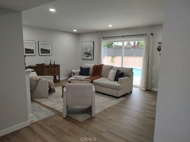 living room featuring baseboards, light wood finished floors, and recessed lighting